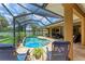 A serene screened-in pool area with a kidney-shaped pool, lounge chairs, lush landscaping, and patio at 5359 90Th Avenue E Cir, Parrish, FL 34219