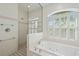 A well lit bathroom featuring a soaking tub, walk in shower, neutral color scheme and plantation shutters at 5584 Eastwind Dr, Sarasota, FL 34233