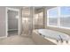 Bright bathroom featuring a soaking tub under a window and a glass door shower, next to a walk-in closet at 5981 Willows Bridge Loop, Ellenton, FL 34222