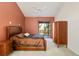 A bedroom with a sliding glass door to a balcony, brown colored walls, and a matching colored leather bed and wooden closet at 6101 34Th W St # 11C, Bradenton, FL 34210