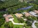 Aerial view of home near a pond; property has a screened-in pool and is surrounded by greenery at 7003 Lancaster Ct, University Park, FL 34201