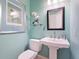 Small bathroom features light blue walls, pedestal sink, and decorated with modern art at 7003 Lancaster Ct, University Park, FL 34201