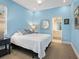 Light blue bedroom featuring a white bed, minimalist design and a full ensuite bathroom at 7003 Lancaster Ct, University Park, FL 34201