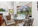 Cozy dining area overlooking the screened-in pool, featuring a glass-top table and stylish plaid chairs at 7003 Lancaster Ct, University Park, FL 34201