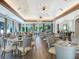 A spacious dining room has modern light fixtures, large windows with beautiful views, and tables set for a delightful meal at 7003 Lancaster Ct, University Park, FL 34201