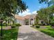Stately home with a clay tile roof, three-car garage and a circular driveway with mature landscaping at 7003 Lancaster Ct, University Park, FL 34201