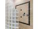 Modern bathroom shower featuring glass block partition and travertine tile with a dark border at 7003 Lancaster Ct, University Park, FL 34201