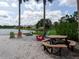 Relaxing beach area with picnic table and colorful Adirondack chairs overlooking the lake at 8078 Stirling Falls Cir, Sarasota, FL 34243