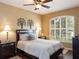 Comfortable bedroom featuring a large bed, ceiling fan, bedside tables, and large window with shutters at 8078 Stirling Falls Cir, Sarasota, FL 34243