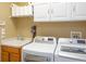 Organized laundry room with washer, dryer, sink, storage cabinets, and convenient shelving for supplies at 8078 Stirling Falls Cir, Sarasota, FL 34243