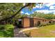 Inviting tan home with manicured lawn, decorative landscaping, and mature shade tree in a quiet neighborhood at 8472 60Th N St # 702, Pinellas Park, FL 33781