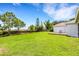 Expansive backyard featuring a lush green lawn, a wooden deck, mature trees, and privacy hedges at 9402 71St E Ave, Palmetto, FL 34221