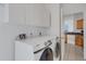 Well-lit laundry room features white cabinets, Samsung washer/dryer, and doorway to kitchen at 9402 71St E Ave, Palmetto, FL 34221