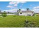 Lush green backyard with tropical plants, lawn, and screened patio extending from the house at 107 Van Dyck Dr, Nokomis, FL 34275