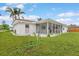 Home backyard with a screened-in porch and manicured green lawn surrounded by a white rock border at 107 Van Dyck Dr, Nokomis, FL 34275