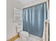 Bright bathroom features a toilet, shower with blue curtain, and window with blinds at 107 Van Dyck Dr, Nokomis, FL 34275