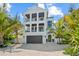 Stunning three-story home boasts multiple balconies, a dark-stained garage door, and verdant palm trees at 109 Palmetto Ave, Anna Maria, FL 34216