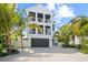 Beautiful white home with striking black accents, multiple balconies, a garage, and tropical landscaping at 109 Palmetto Ave, Anna Maria, FL 34216