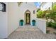 Charming home entrance featuring a unique arched doorway, lush greenery, and decorative turquoise planters at 109 Palmetto Ave, Anna Maria, FL 34216