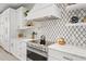 Close up of sleek white cabinets, marble countertops, and designer backsplash in a well-equipped kitchen at 109 Palmetto Ave, Anna Maria, FL 34216