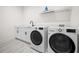 Functional laundry room with modern washer, dryer, sink, storage, and light wood-look flooring at 109 Palmetto Ave, Anna Maria, FL 34216