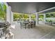 Spacious covered patio with dining area, grill, lounge chairs, and tropical landscaping surrounding the pool at 109 Palmetto Ave, Anna Maria, FL 34216