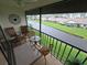 Relaxing screened balcony with seating overlooks a tranquil water view and landscaped grounds at 1211 Capri Isles Blvd # 116, Venice, FL 34292