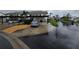 Exterior of condo featuring covered parking, landscaping, and street view on a rainy day at 1211 Capri Isles Blvd # 116, Venice, FL 34292