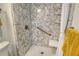 Standing shower featuring safety grab bars, seat, marble-patterned walls, and shower curtain at 1250 N Portofino Dr # 208, Sarasota, FL 34242