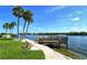 Scenic waterfront view with palm trees, a wooden dock, lush greenery, and tranquil blue waters at 1250 N Portofino Dr # 208, Sarasota, FL 34242