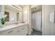 Well-lit bathroom with marble countertop vanity, decorative mirror, and shower at 137 Woodland Pl, Osprey, FL 34229
