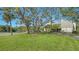 Inviting exterior view of the home showcasing the manicured lawn, mature trees, and peaceful surroundings with a serene lake at 137 Woodland Pl, Osprey, FL 34229
