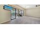 An open living area features carpet floors, a ceiling fan, and a view to the outdoor balcony at 137 Woodland Pl, Osprey, FL 34229