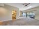 An open living area features carpet floors, a ceiling fan, and a view to the outdoor balcony at 137 Woodland Pl, Osprey, FL 34229