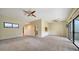 An open living area features carpet floors, a ceiling fan, and a view to the outdoor balcony at 137 Woodland Pl, Osprey, FL 34229