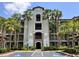 Beautiful condo complex, showcasing an arched entrance and multiple balconies surrounded by palm trees at 16804 Vardon Ter # 307, Bradenton, FL 34211