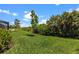 Beautiful backyard featuring vibrant green grass, young trees, and tropical plants at 17632 Santorini Ct, Venice, FL 34293