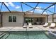 Relaxing backyard with a screened-in pool, patio dining, and sun loungers for ultimate comfort at 17632 Santorini Ct, Venice, FL 34293