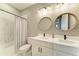 Bathroom with double vanity, round mirrors, and modern lighting at 17898 Cherished Loop, Bradenton, FL 34211