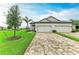 Charming two-story home showcasing a three-car garage, brick driveway, and beautifully landscaped front yard at 17898 Cherished Loop, Bradenton, FL 34211