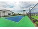 Well-maintained tennis court enclosed with a black fence, lush green backdrop, and palm tree accents at 17898 Cherished Loop, Bradenton, FL 34211