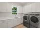Well-equipped laundry room features white cabinetry, a window, and a modern washer and dryer set at 1954 Goldenrod St, Sarasota, FL 34239