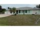 Exterior view of a light green single-story home with a well-manicured front lawn and mature palm trees at 20170 Tralee Dr, Port Charlotte, FL 33952