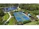Aerial view of multiple pickleball courts next to a lake and walking path in a lush community at 208 Ariano Ave, Nokomis, FL 34275