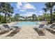 Poolside lounge area with cushioned chairs under palm trees on a brick-paved surface at 208 Ariano Ave, Nokomis, FL 34275