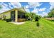Expansive backyard featuring vibrant landscaping, healthy lawn, and a glimpse of the property's screened lanai at 2085 Mattamy Ct, Venice, FL 34292
