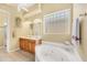 Bathroom features a double sink vanity, a soaking tub, glass block window, and a tiled floor at 2085 Mattamy Ct, Venice, FL 34292