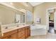 Bathroom featuring a double sink vanity, large mirror, tiled floor, and a separate tub and shower at 2085 Mattamy Ct, Venice, FL 34292
