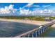 Expansive beach view with wooden pier, coastline, and restaurant under a blue sky with scattered clouds at 2085 Mattamy Ct, Venice, FL 34292
