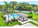 Community pool with a cabana, surrounded by lush landscaping and a white picket fence at 2085 Mattamy Ct, Venice, FL 34292